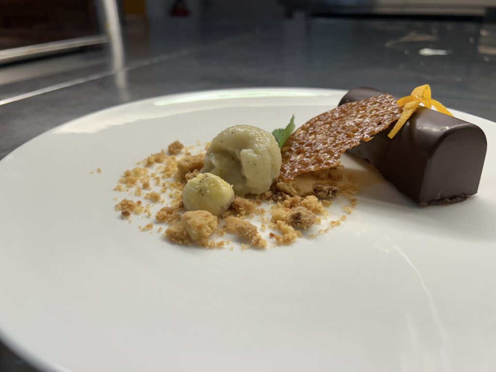 Delicate chocolade dessert met romige ijs en knapperige garnituren, perfect gepresenteerd voor een verfijnde smaakervaring.