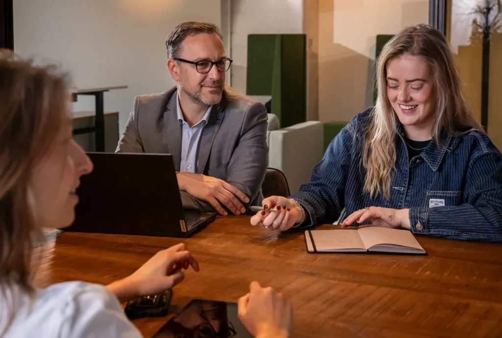 Collega's zitten aan een tafel en hebben overleg.