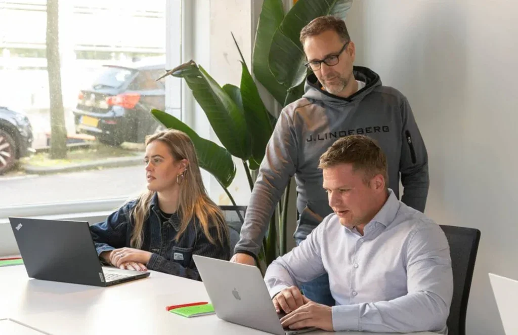 Drie collega's overleggen aan een bureau.