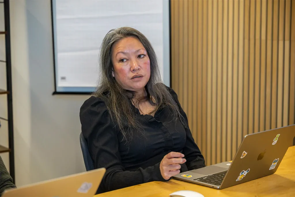 Een collega zit aan tafel in een vergaderruimte en kijkt serieus.