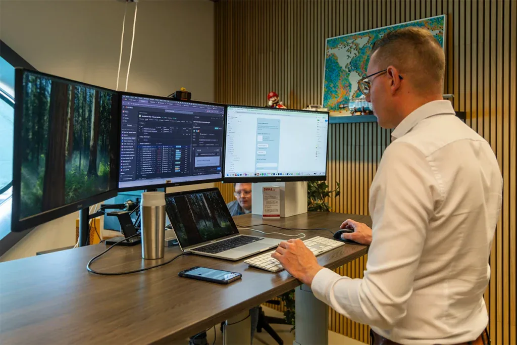 Een programmeur is staand aan het werk achter zijn bureau op kantoor.