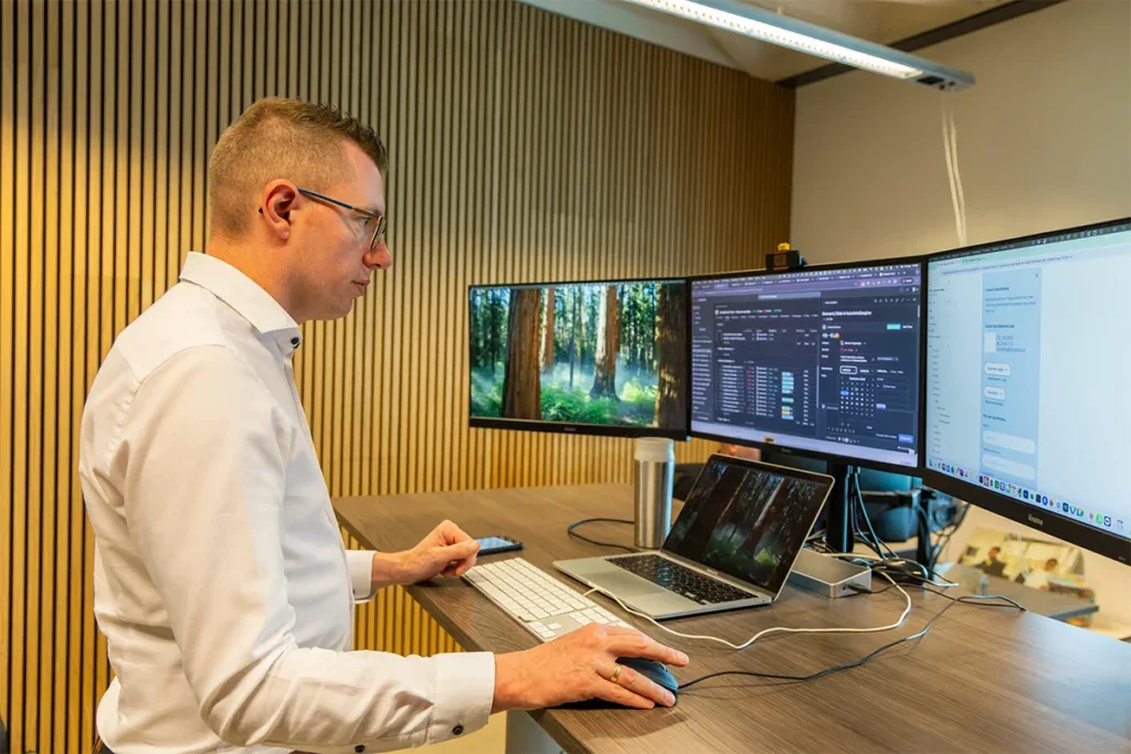 Een programmeur is staand aan het werk achter zijn bureau op kantoor.