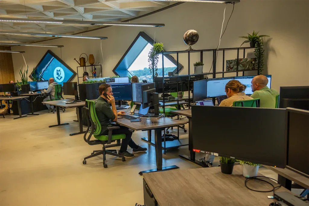 Een aantal collega's is aan het werk op kantoor en een collega belt met een klant.