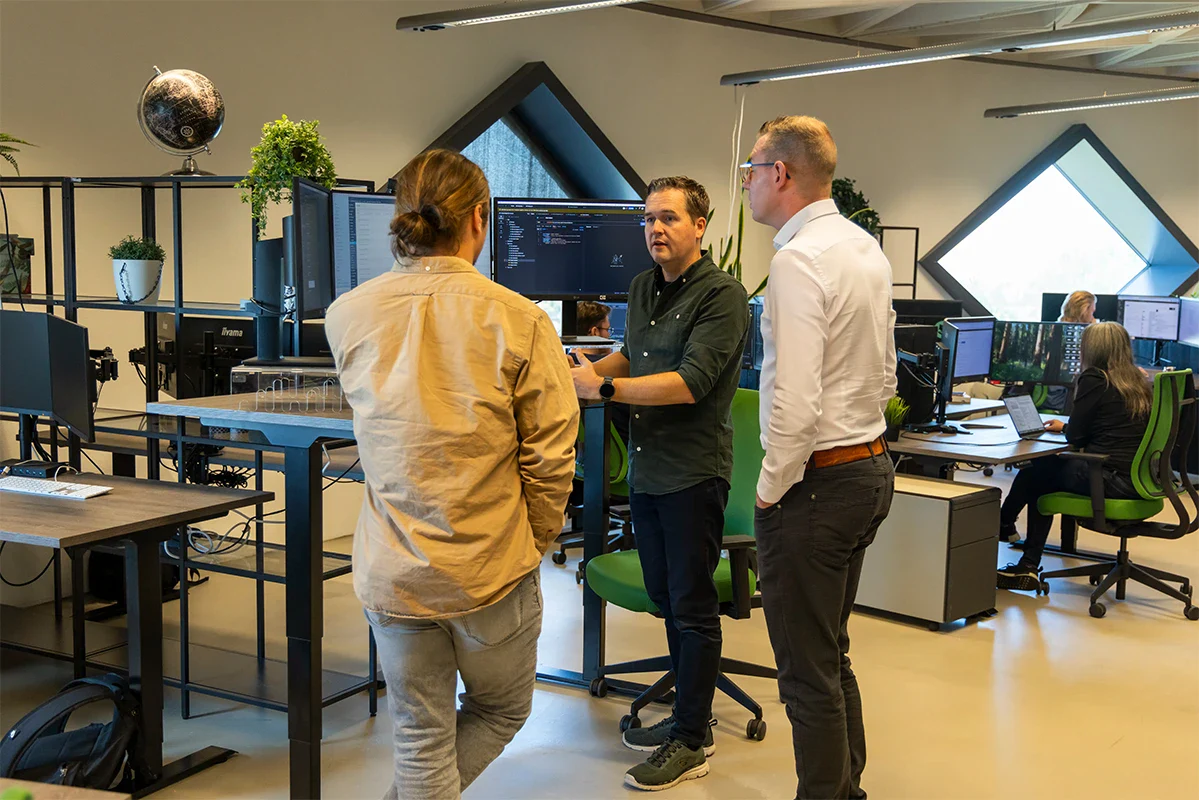 Programmeeurs overleggen staand achter een bureau op kantoor.