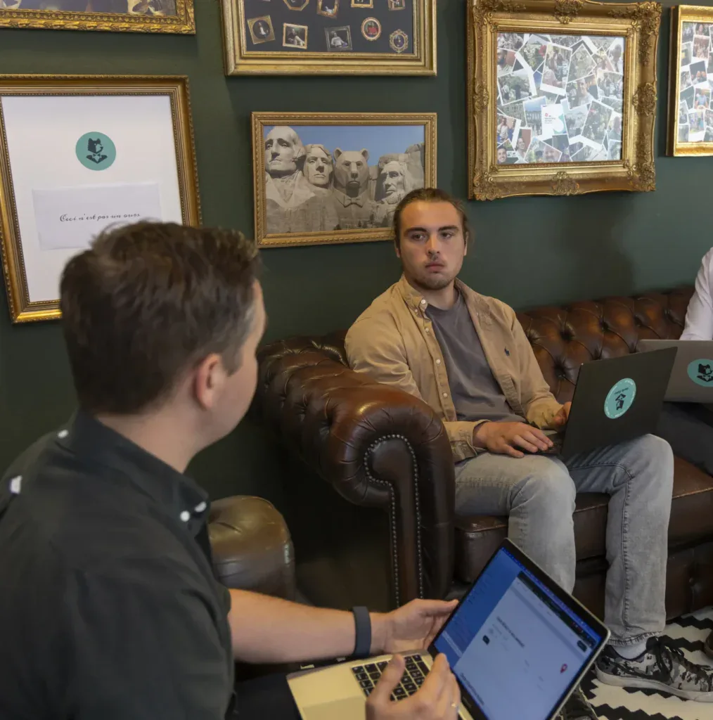 Developers overleggen met hun laptop op schoot op een leren bank.