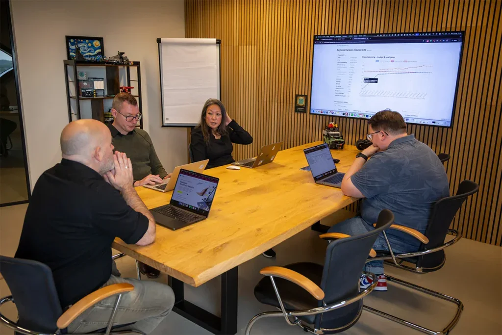 Team zit aan tafel en overlegt tijdens een meeting in een vergaderruimte.