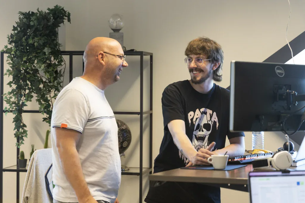 Programmeurs lachen met elkaar voor een bureau op kantoor.