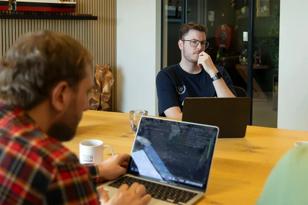 Front end developer kijkt serieus tijdens een meeting in een vergaderkamer.