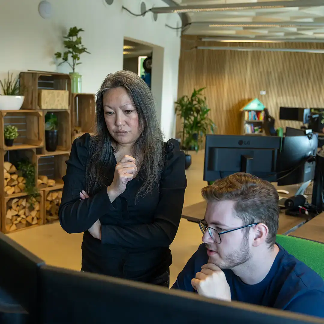 Collega's kijken samen naar een beeldscherm en overleggen.