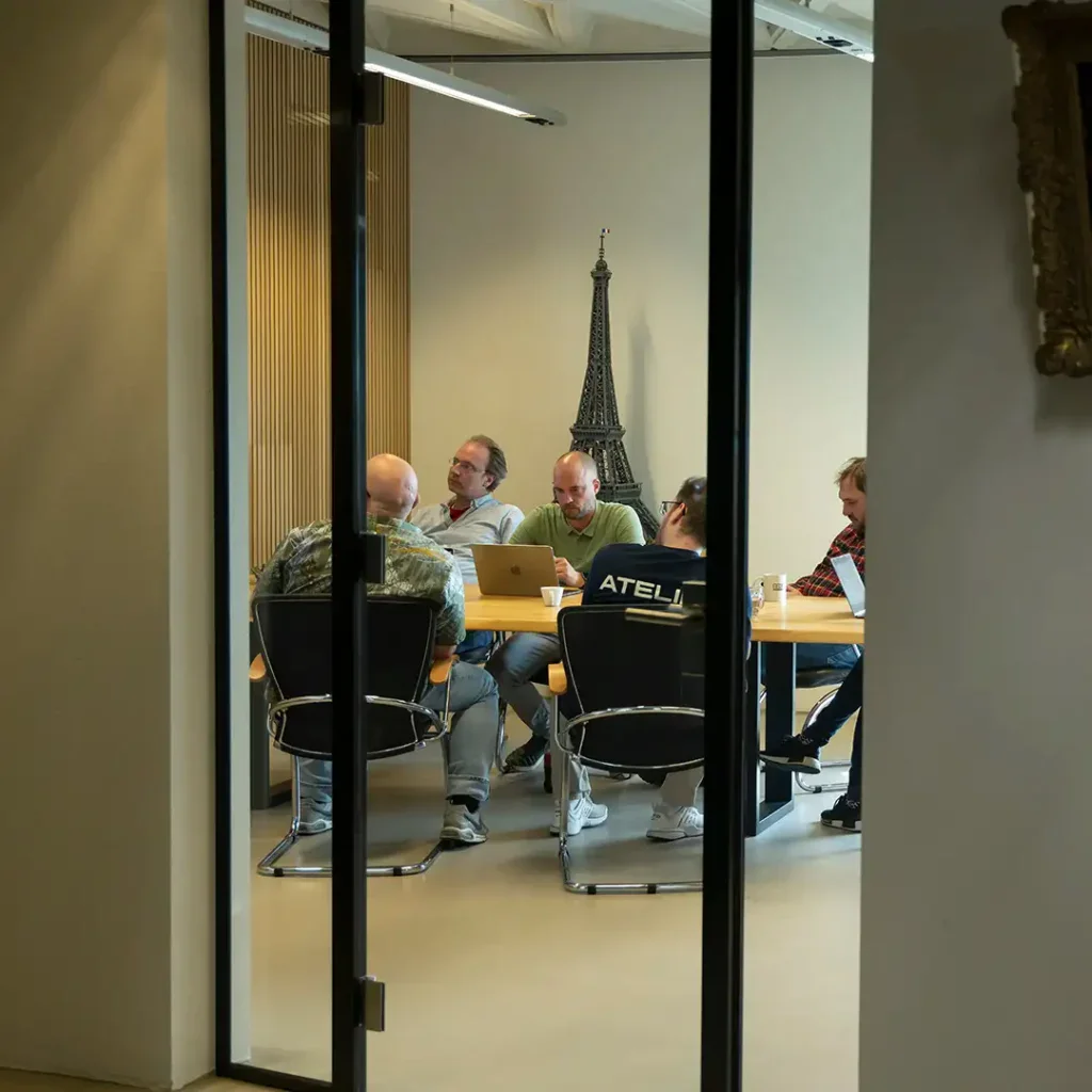 De collega's zitten aan een tafel tijden de teammeting in de boardroom.