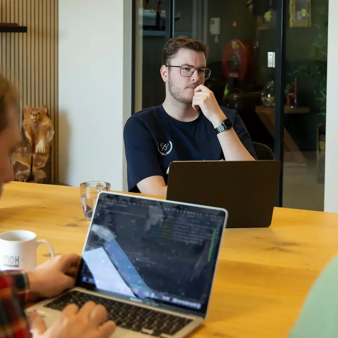 Twee collega's staan en overleggen in een vergaderkamer op kantoor.