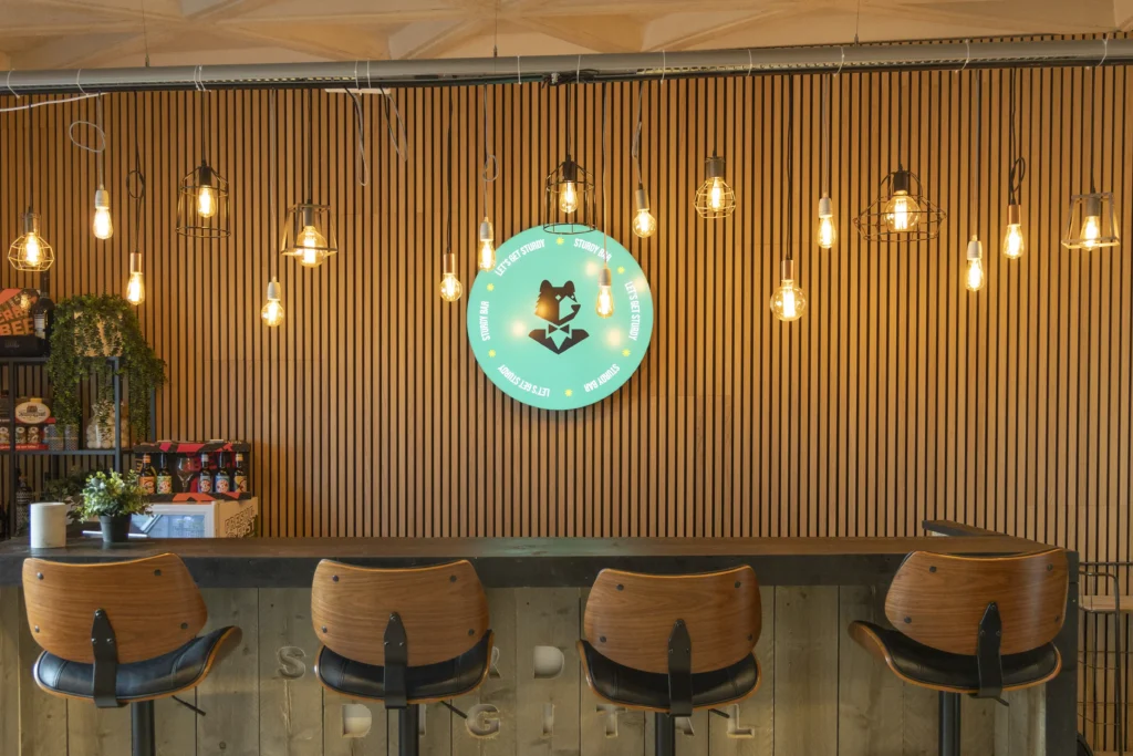 Een houten bar met daarboven lichtjes een lichtbak met het Sturdy logo.